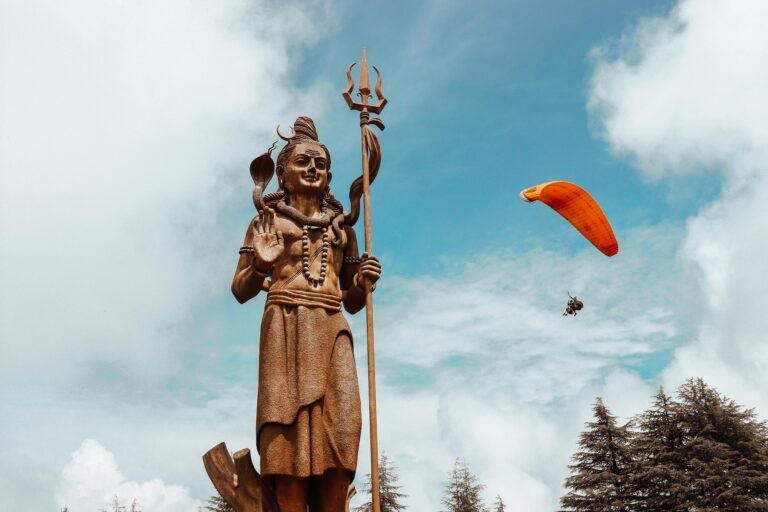 Home Majestic statue of Shiva with paraglider in sky, Dalhousie, India.