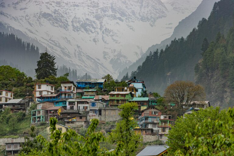 Home Scenic view of a colorful village in Manali with the snowy Himalayas in the background.